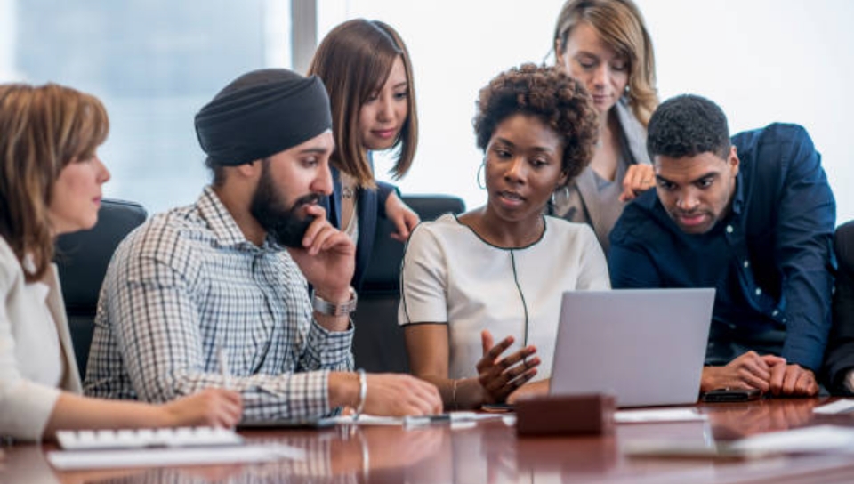 Group of people huddled up in a conference room looking at reports and making decisions