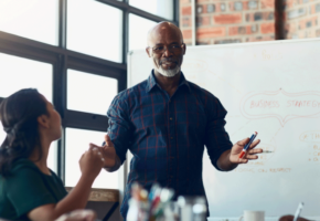 Man in meeting presenting resource management solutions to his team in front of whiteboard